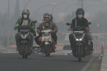 Riders with mask paasing through haze in Indonesia. Photo: AP