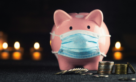 A pink piggy bank wearing a face mask, surrounded by stacked coins, symbolizing the economic impact of healthcare expenses, pandemics, and financial burdens.