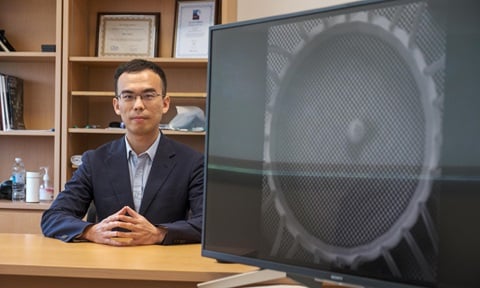 Asst Prof Shen Yijie with a photo of a water-waves experimental set-up
