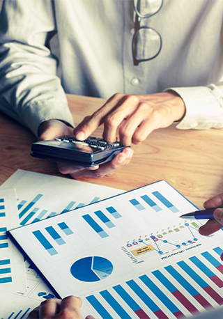 Someone using a calculator, while checking financial data and charts