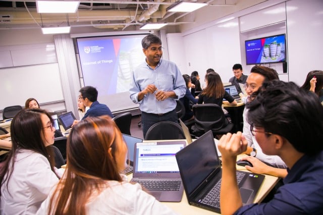 Nanyang Business School students around a table in discussion with professor in class