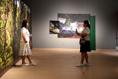 Further Reading: Visitors taking photographs with artwork featuring trees