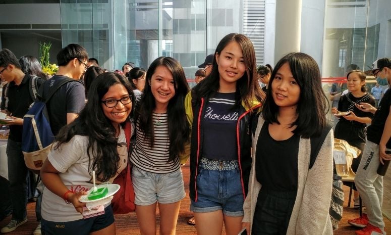 Four freshmen taking a group photo at a tea reception.