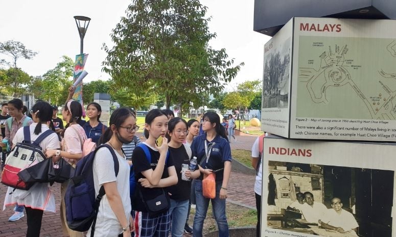 A group of students reading a panel on information of local ethnic groups.