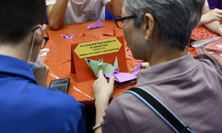 Picture showing a student and a senior citizen making handy craft for Lunar New Year.