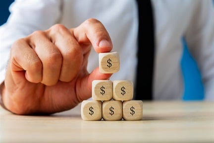 businessman making pyramid shape of wooden dices with dollar sign on them.