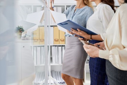 business women with folders and documents writing ideas on whiteboard