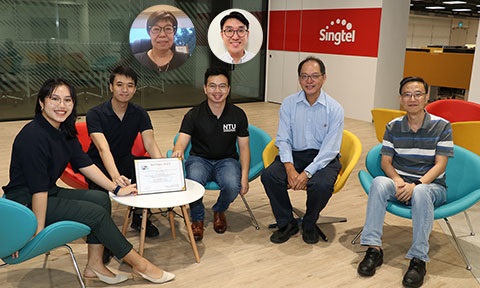 Thumbnail photo of group of researchers and students sitting infront of a small coffee table with a certificate on it.
