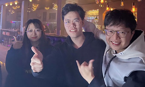 Photo of 3 postgraduates smiling and posing thumb-up.