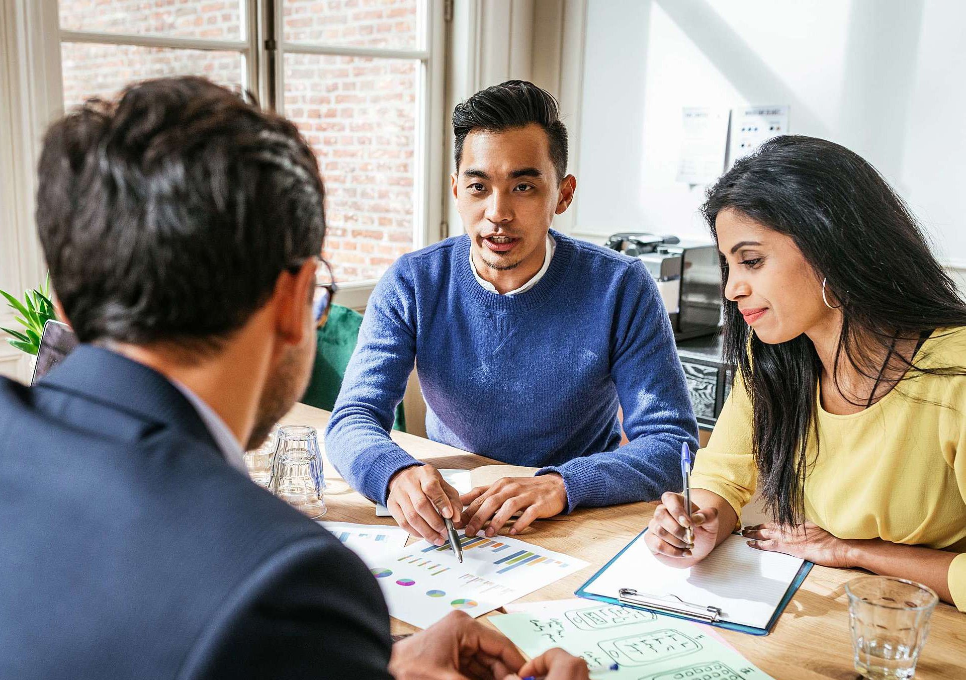 Male student points out data and statistics in a team meeting