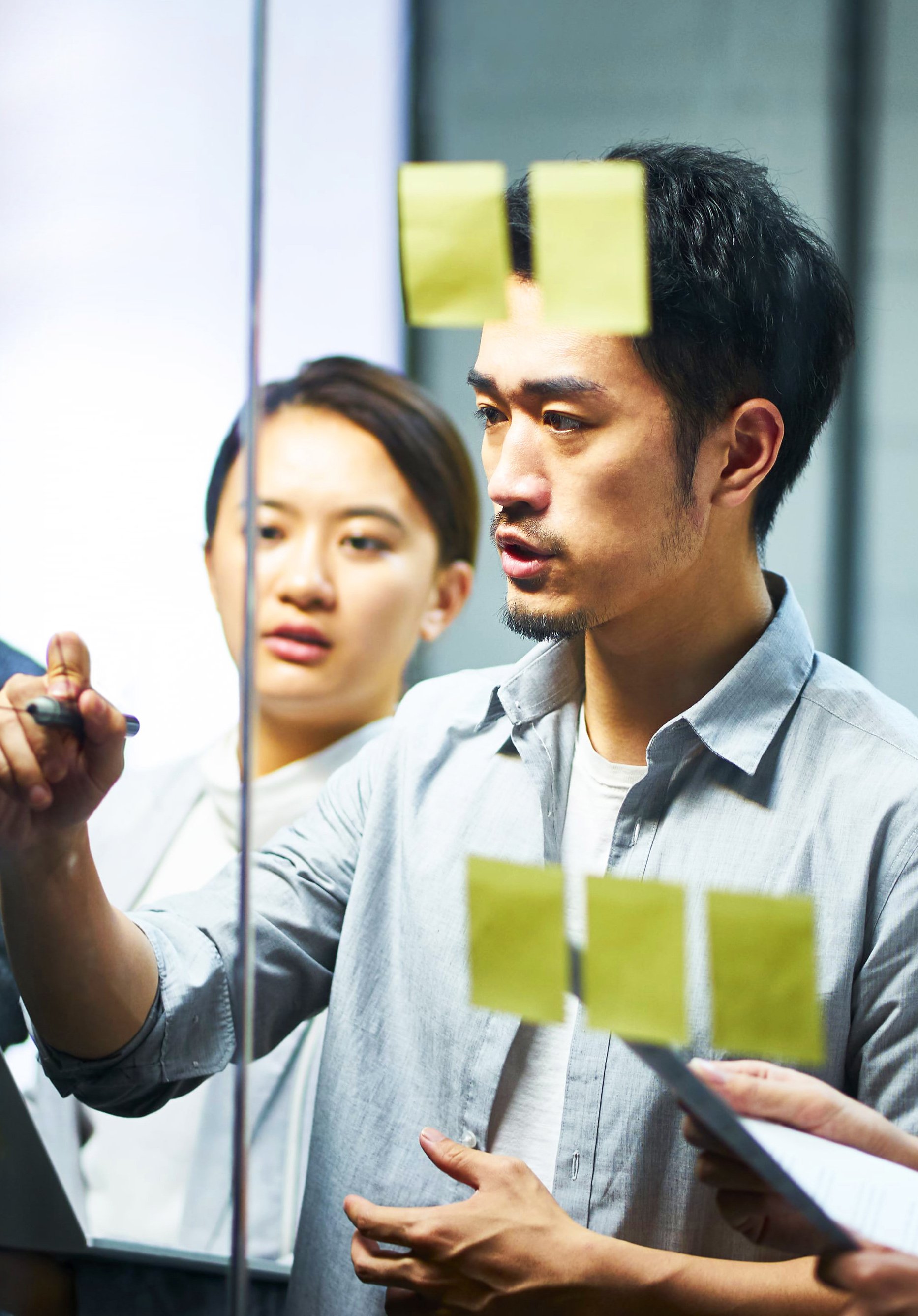 Male student drawing conclusions, linking ideas and writing solutions on a glass board