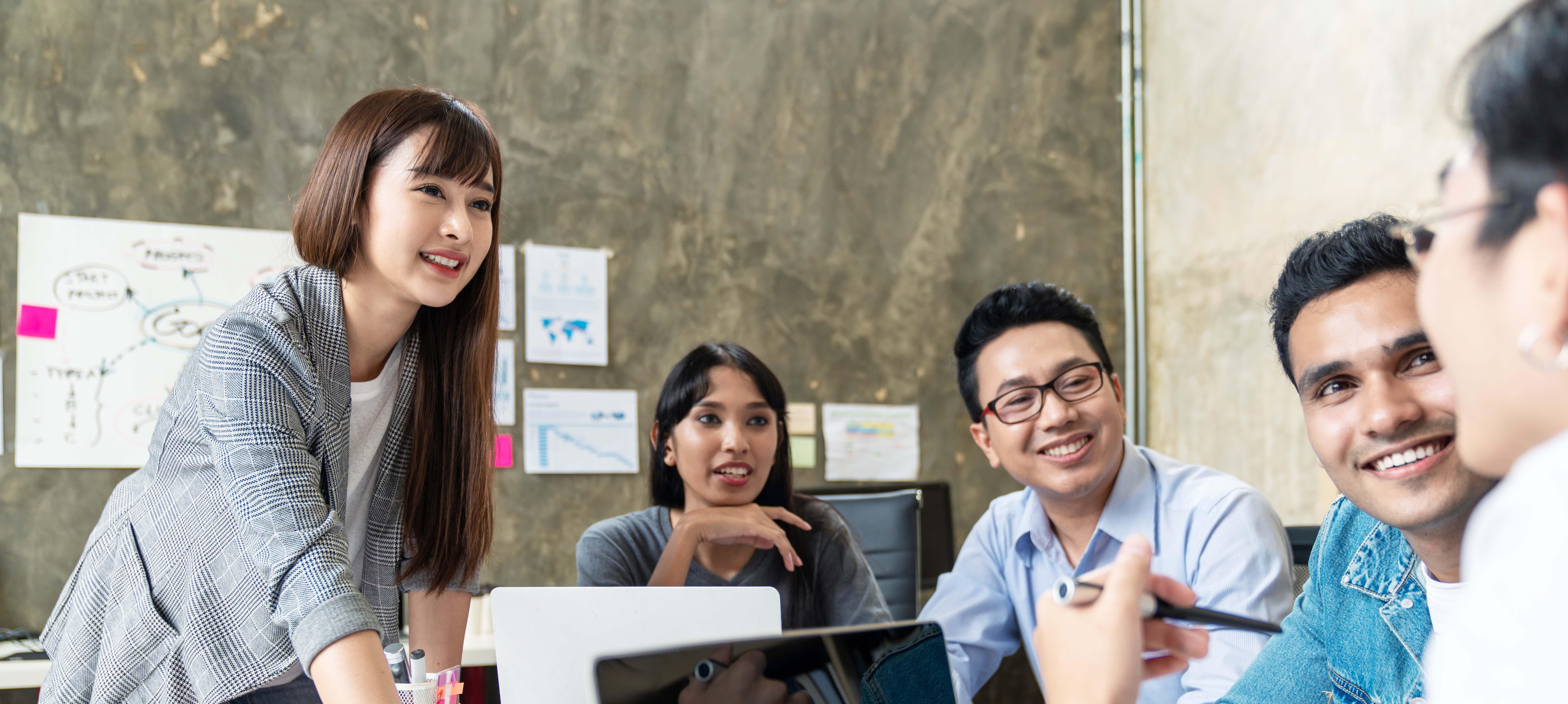 Working adults smiling in a project discussion meeting