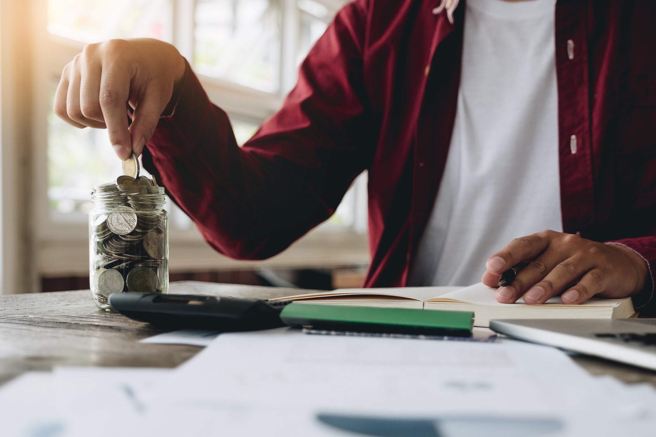Student saving coins in a glass jar for education fund.