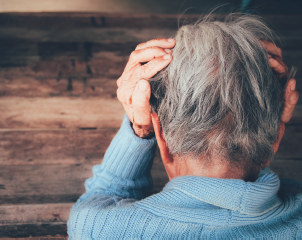 An older gentleman grasping their head in their hands