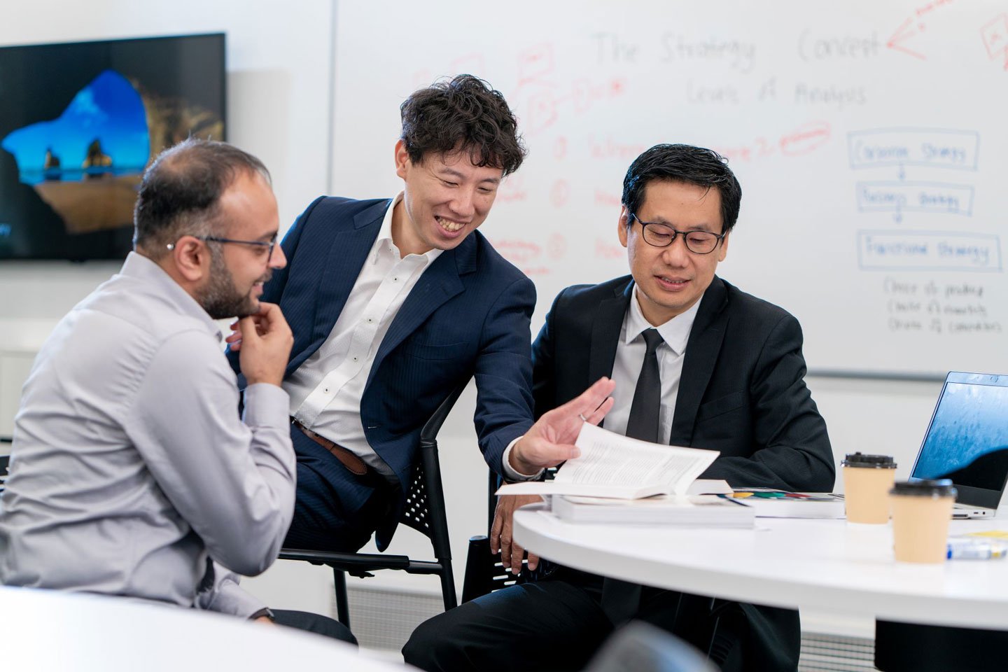 Three Nanyang Fellows MBA students discussing a topic in an NBS lecture room
