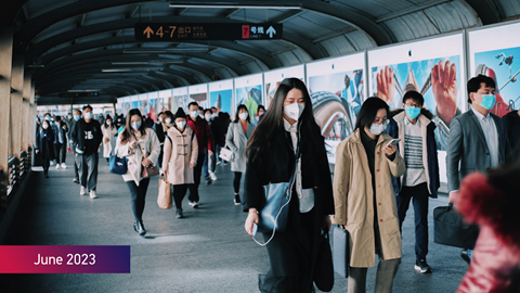 People wearing face masks at a train station with the text June 2023 on image