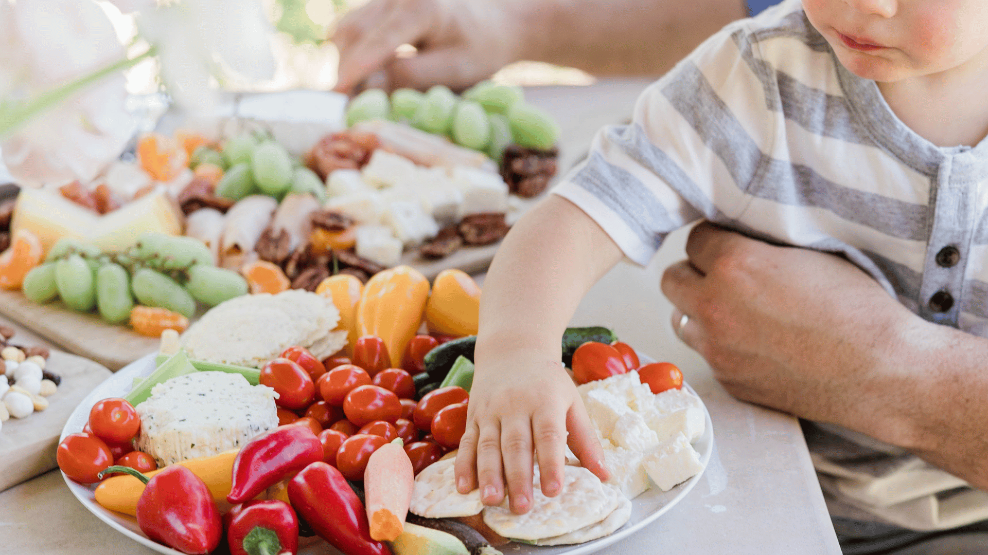 A child placing his hand on a plate full of vegetables