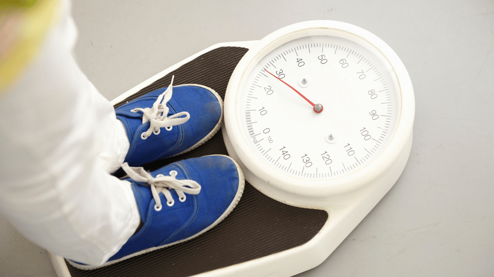 A child stepping on the weighing machine to measure their weight