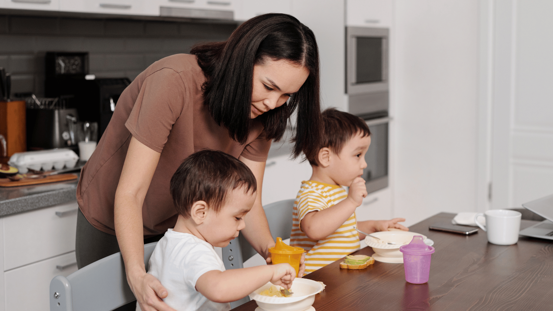 A woman ensuring that her two children are eating their food
