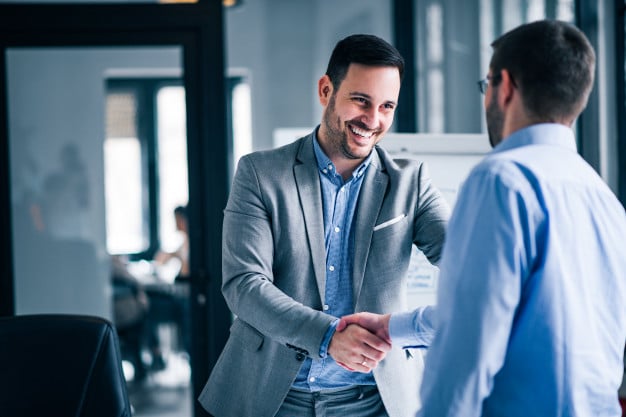 Two men shaking hands in a university classroom