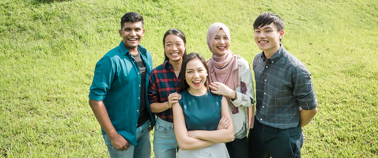 Group Of 5 Smiling Students On A Grass Patch