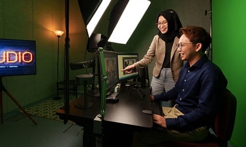 Green Screen Filming With Light And Screen Setup In-Learning I3 Studio. A Man And Malay Woman Looking At Screen Wideshot (720x432px)