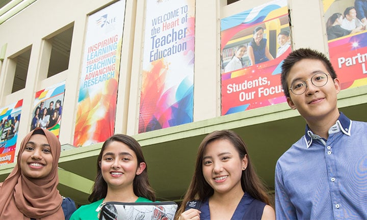 Smiling Group of 4 Students Under NIE Building Banners Low Angle