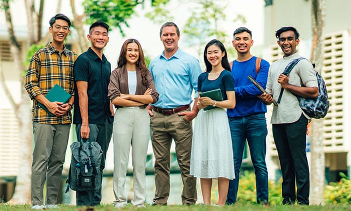 Smiling Group of 7 Young Adult Teachers Chinese Boy Yellow Gingham Plaid Shirt Caucasian Man Light Blue Shirt