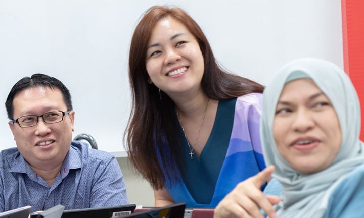 Smiling Group of teachers in blue In Classroom Looking In Distance 2 blue malay tudung (720x432px)