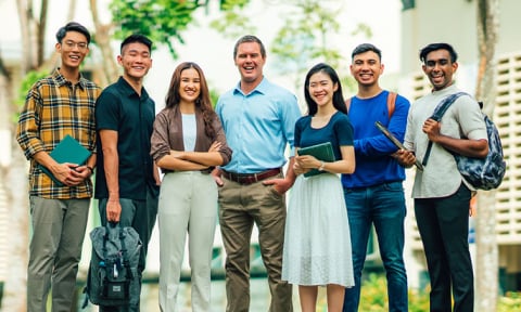 Smiling Group of 7 Young Adult Teachers Chinese Boy Yellow Gingham Plaid Shirt Caucasian Man Light Blue Shirt