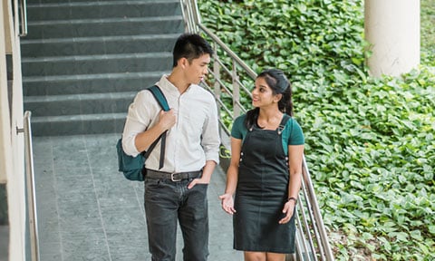 Walking Shot Chinese Boy with Backpack and Indian Girl in Dungaree Dress Talking at Staircase (480x288px)